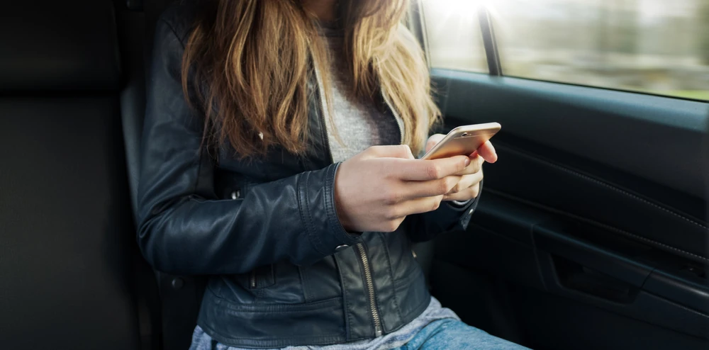 Header Image - teenager on phone in the back seat